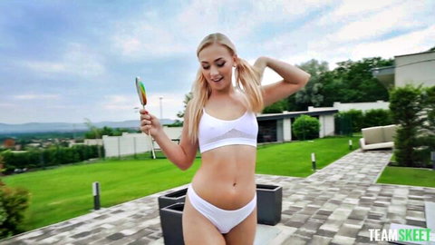 Blonde Jenny Wild in white bikini teasing with lollipop outdoors