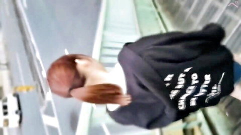Amateur redhead teen in black hoodie walking on urban bridge