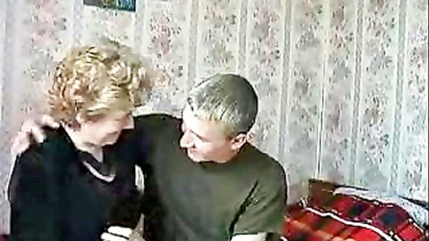 Russian granny with pale skin and curly blonde hair embraces mature man on bed