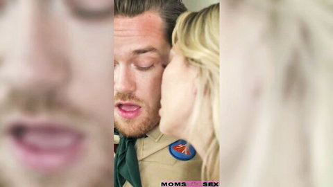 Blonde stepmom whispers intimately to bearded stepson in scout uniform, threesome tease
