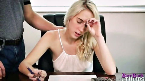 Blonde in sheer white top rubs eyes while man grips her shoulder at office desk