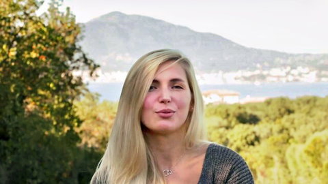 Sexy blonde puckering cock-sucking lips outdoors with sea and mountain view