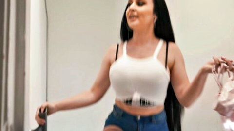 Curvy brunette in revealing white top and denim shorts poses seductively in Brazzers teaser