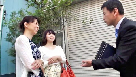 Japanese mother and daughter smiling at suited man in casual outdoor chat