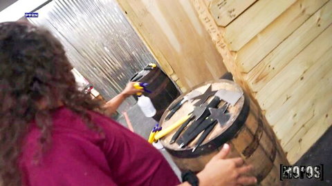 Serena Sterling in pink top, cleaning barrel from behind in workshop