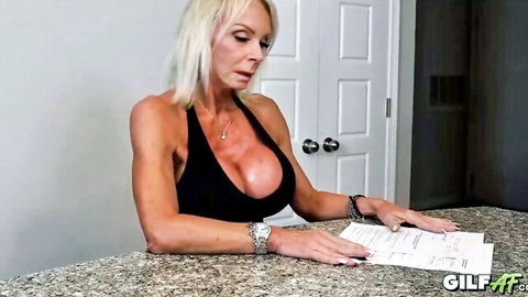 Blonde GILF Summer Angel in low-cut black top, big fake tits cleavage