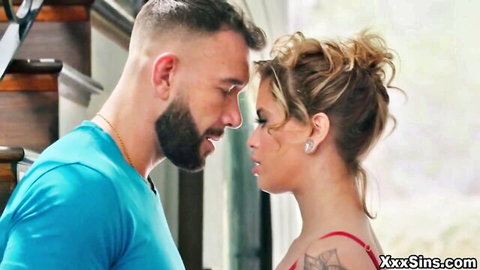 Bearded man in blue shirt intimately kisses blonde in red lingerie during steamy foreplay