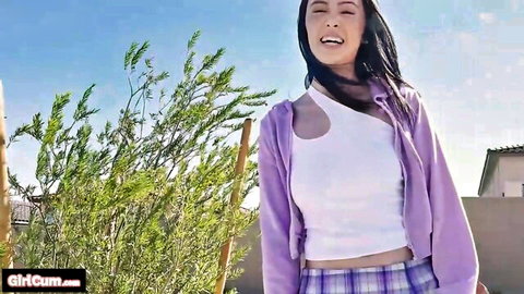Smiling Asian hitchhiker in plaid skirt and crop top outdoors