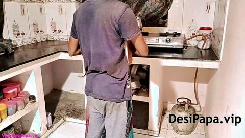 Indian man stands in kitchen wearing t-shirt and pants near gas stove in homemade amateur video