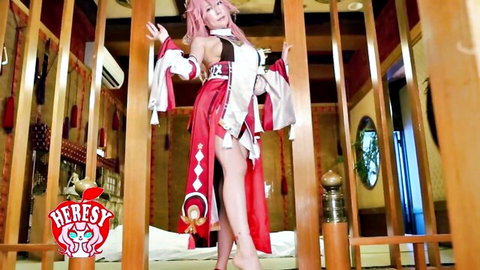 Pink-haired Asian cosplay babe in revealing red dress with thigh slits posing seductively in traditional room