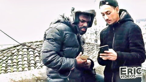 Two guys in jackets and hats check phones outdoors in kinky setup