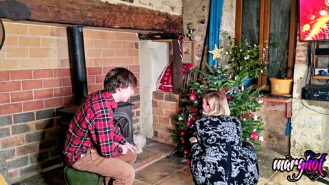 French cougar stepmom in sexy black dress kneels by Christmas tree with young stepson