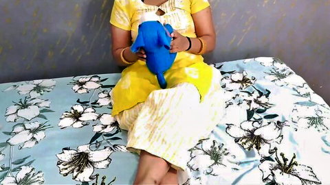 Desi step-auntie in yellow salwar kameez holding blue elephant toy