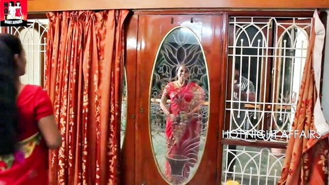 Two busty mature Indian women in sexy sarees posing seductively in bedroom mirror reflection