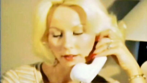 Vintage blonde MILF seductively talking on retro phone with parted lips