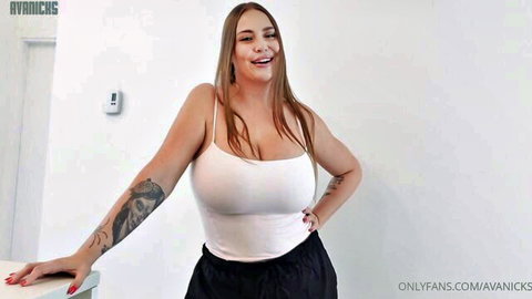 Tattooed busty woman smiling with massive tits spilling from tight white tank top