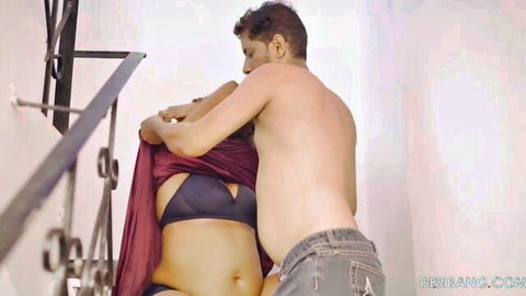 Shirtless guy gropes busty brunette's black bra and belly on stairs