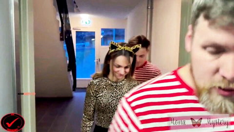 Leopard print cat ears woman smiles teasingly at bearded striped shirt guy in hallway
