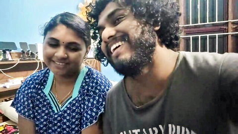 Smiling Indian wife in saree blouse and bearded husband couple selfie in bedroom