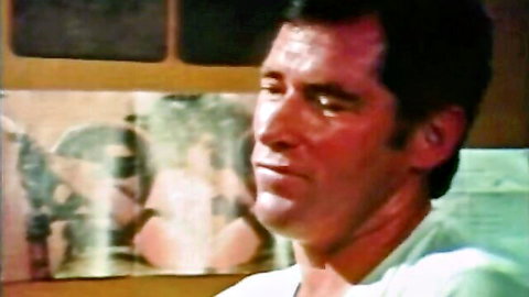 Vintage gay porn thumbnail: handsome man in white shirt, thoughtful gaze, Joe Gage Films style