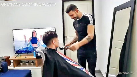 Tattooed muscular barber trimming handsome seated client's hair in bedroom with OnlyFans promo on TV