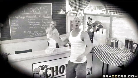Blonde waitress and muscular guy smiling behind Chicko's diner counter