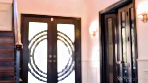 Blurry elegant wooden double doors with circular design in warmly lit pink hallway interior
