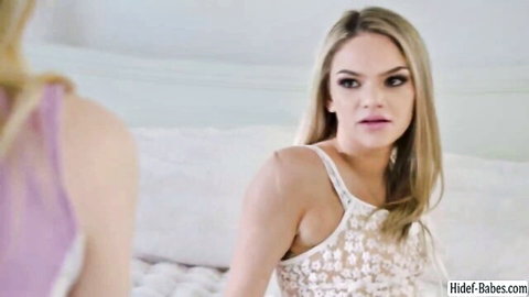 Two skinny blonde teens in sheer lingerie stare intensely at each other on bed