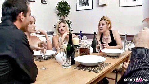 Busty blonde wives in lingerie toasting champagne with husbands at swinger dinner party