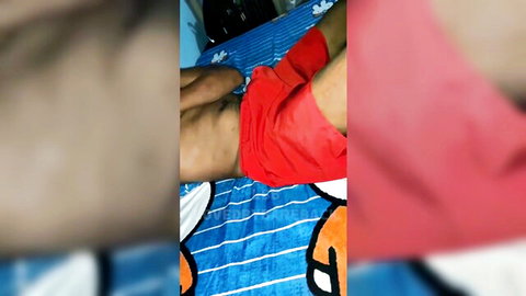Filipino guy teases big cock bulge pulling down red shorts on bed