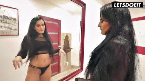 Lexi Dona in sheer black top and thong, posing seductively in mirror