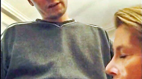 POV of smirking man in gray sweatshirt towering over blonde mature woman's face ready to suck cock