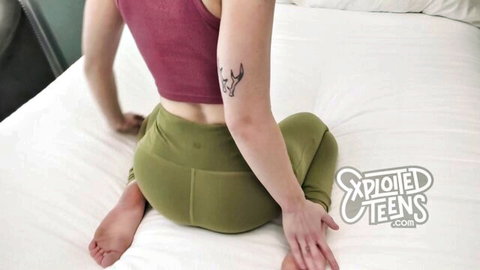 Teen girl sitting on bed from behind in tight green yoga pants showing off her ass
