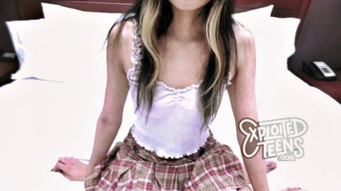 Skinny long-haired Asian teen in white camisole top and plaid miniskirt teasing spread-legged on bed