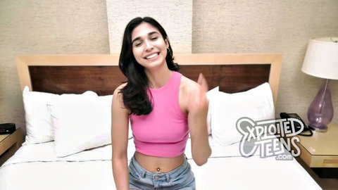 Hot Latina teen smiling in pink tank top and jeans on bed