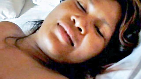 Closeup of black babe with eyes closed moaning in ecstasy lying topless on bed