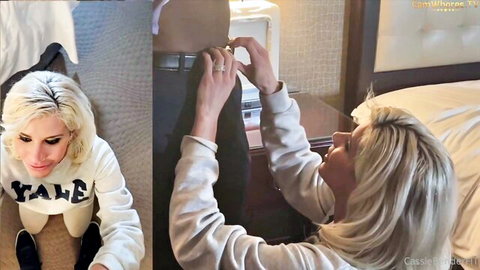 Blonde Cassidy Banks in Yale sweatshirt kneels pulling down man's pants in hotel room