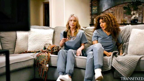 Two sexy nurses in tight blue scrubs lounging smiling on couch