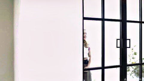 Playful blonde babe peeking through glass door in crop top and skirt teasing
