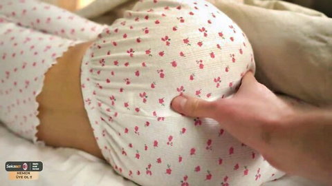 Man's hand squeezing woman's bare juicy ass in pink floral lingerie on bed
