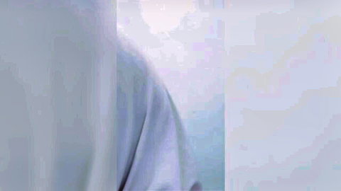 Blurry close-up of white fabric folds or pale skin in amateur tease