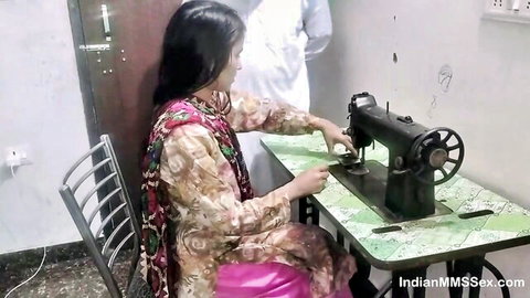 Indian woman in colorful salwar kameez sewing on black machine with man watching homemade amateur video