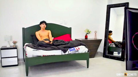 Shirtless young Asian hunk lounging on bed with mature Latina woman reflected in mirror