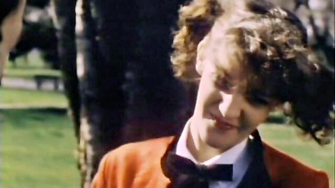 Vintage 1979 thumbnail of curly-haired teen in orange blazer and bow tie outdoors