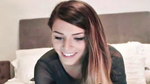 Smiling webcam teen babe in sheer black top revealing perky tits and nipples on bed
