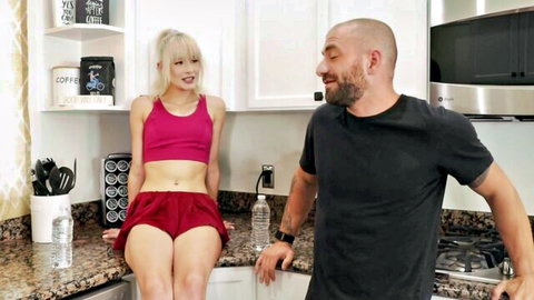 Jessie Saint in pink crop top and shorts, teasing man in kitchen roleplay
