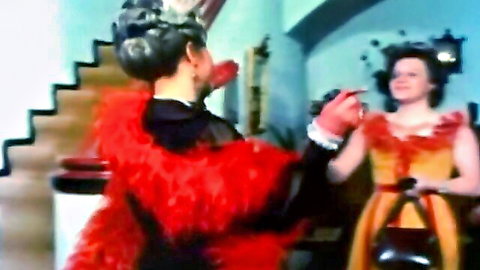 Vintage German teens in feathery red and orange dresses sharing intimate moment in threesome