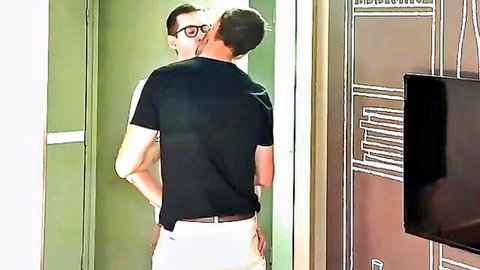 Gay couple passionately kissing and embracing in bedroom doorway foreplay