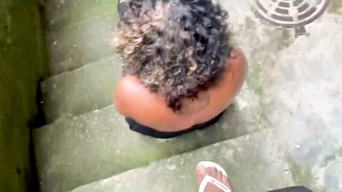 Curly-haired ebony stepdaughter sitting on outdoor stairs in black outfit