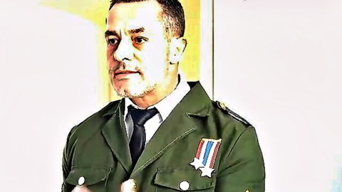 Serious military man in green uniform with medals and tie posing confidently